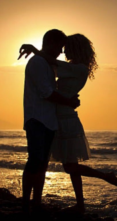 Couple enlacé au coucher de soleil sur la plage